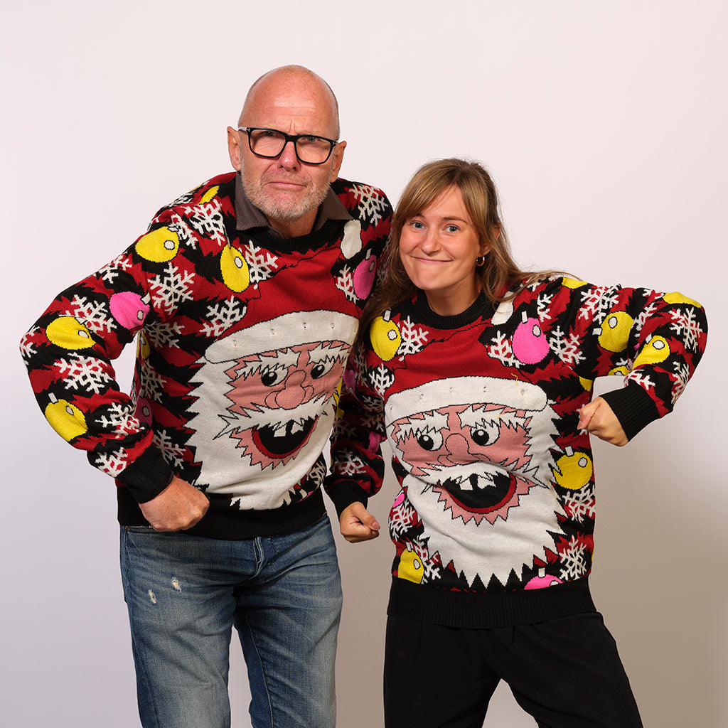 En mand og en dame poserer i en julesweater med et julemandshoved.